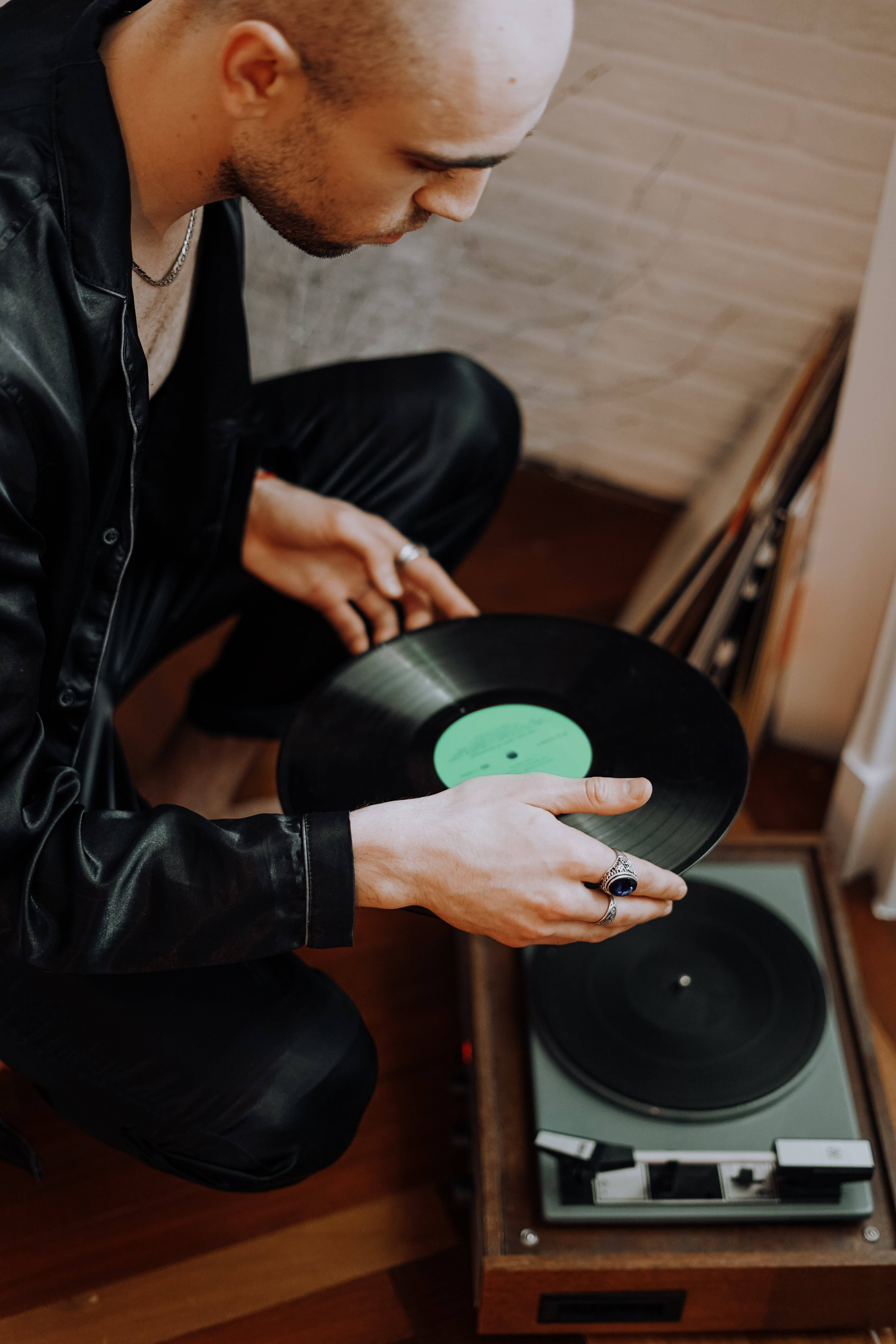 Young man putting a vinyl record on a turntable
